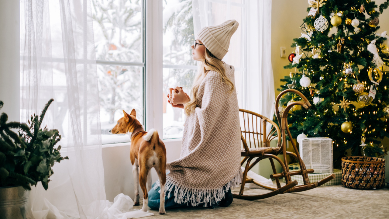 Woman with dog by Christmas tree.
