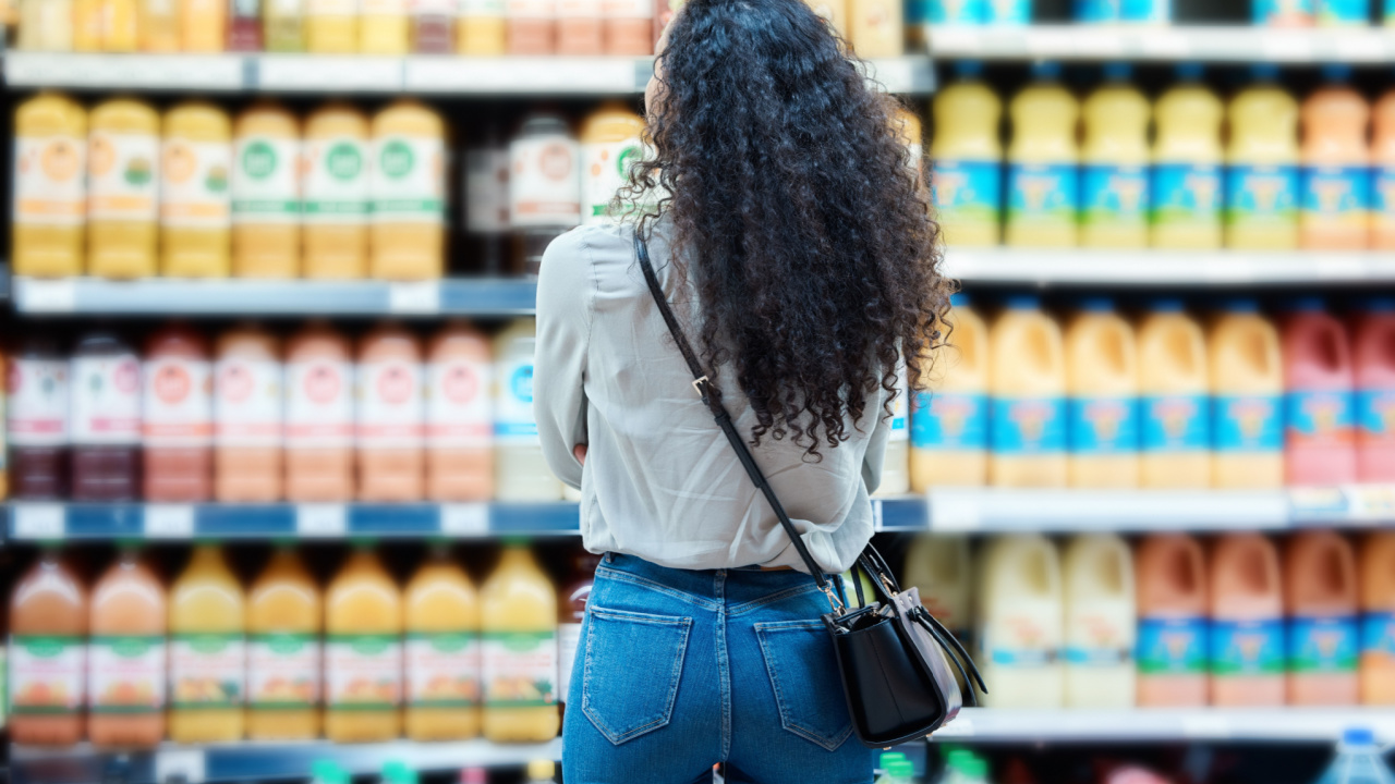 Woman looking high and low at drinks at a grocery store.