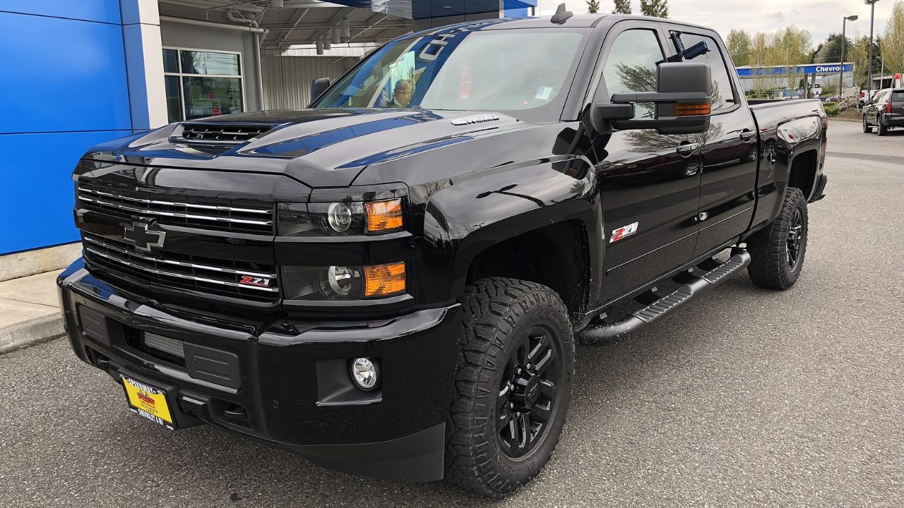 An all-black 2018 Chevy Silverado Z71 2500 HD Midnight Edition in a car dealership parking lot.