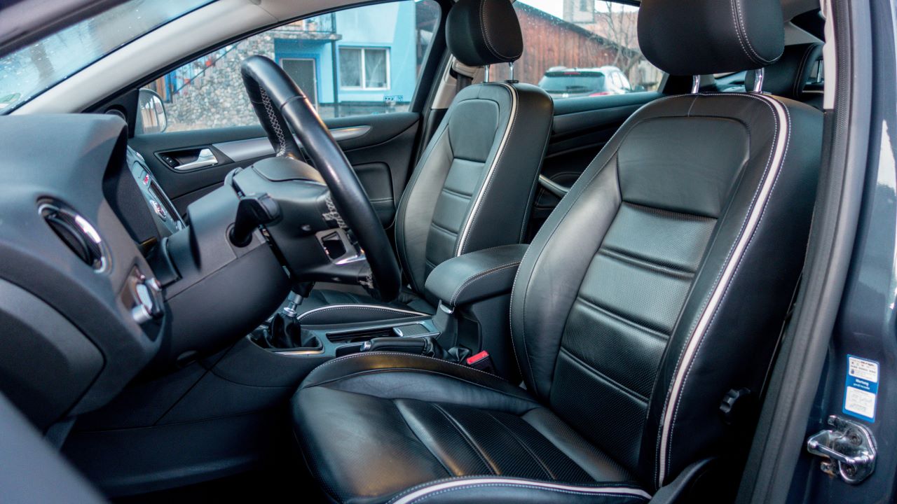 Close up view of perforated black leather car interior. Manual transmission, electric memory seats, heated and ventilated seats, panoramic roof. Interior detail. Modern car, comfortable seats.