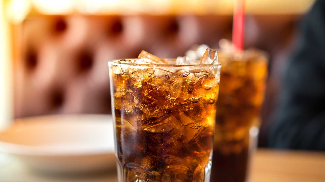 Double cool ice soft drink cola carbonated liquid fresh food with soda water, white dish on wooden table with handsome man sitting brown sofa in pizzeria restaurant.
