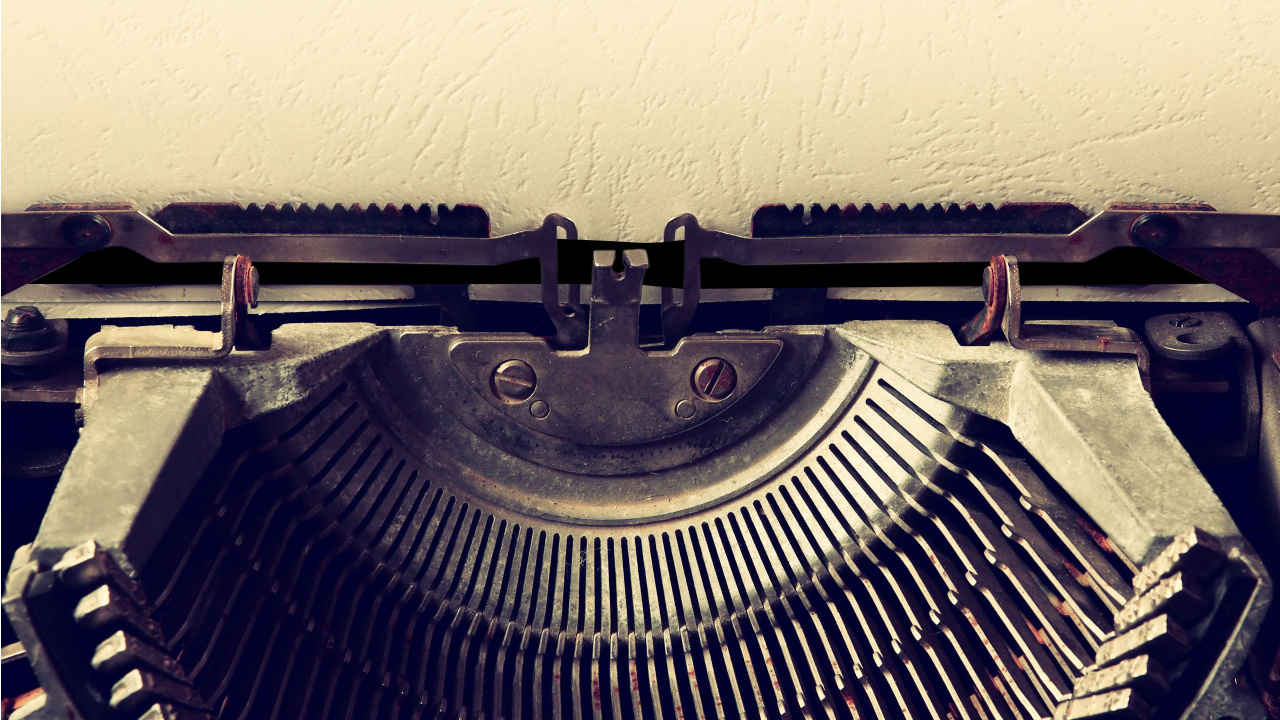 A blank piece of paper and a typewriter.